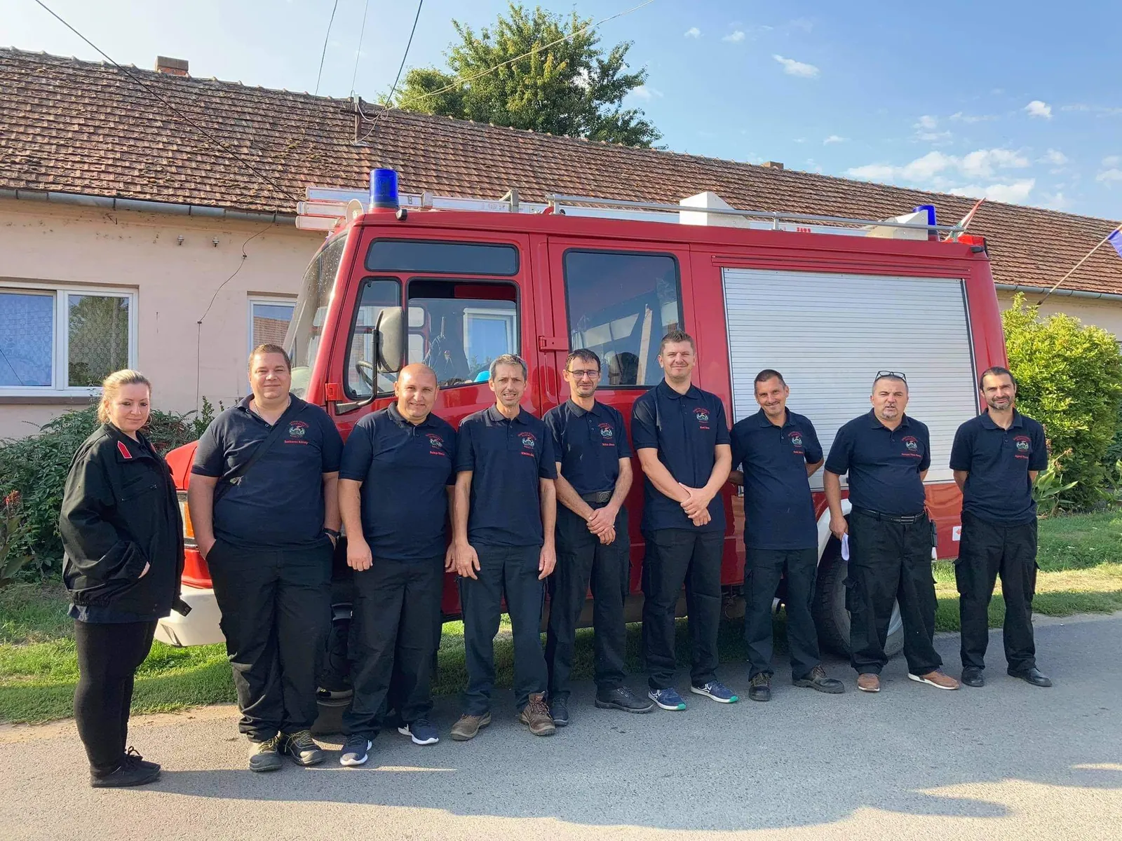 A mentőcsoport és az egyesület tagjai egyenruhában a tűzoltóautó előtt