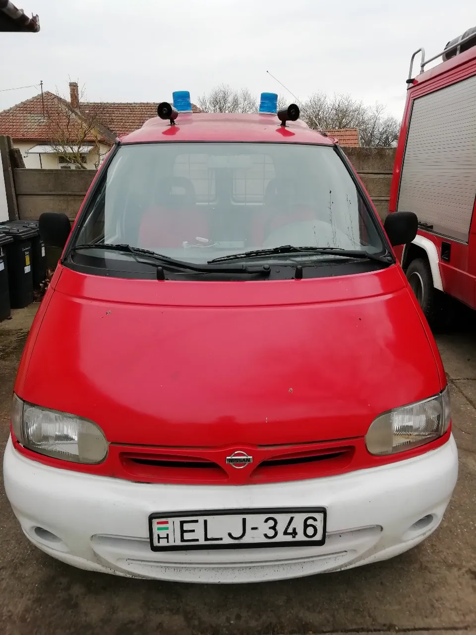 A piros Nissan Vanette Cargo kék villogóval